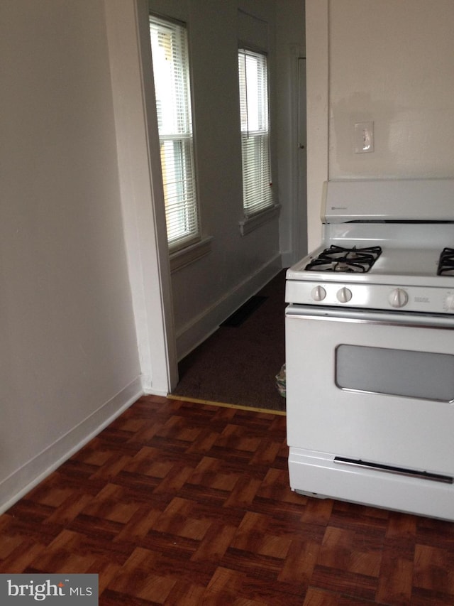 kitchen featuring baseboards, visible vents, and white gas stove