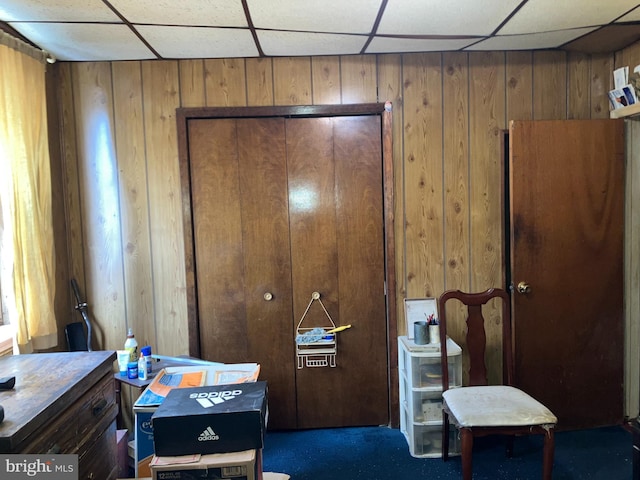 bedroom featuring a drop ceiling and wooden walls