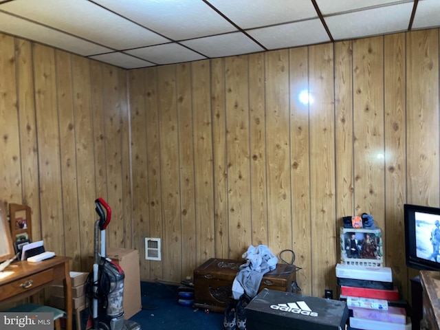 interior space with wooden walls, visible vents, and a drop ceiling