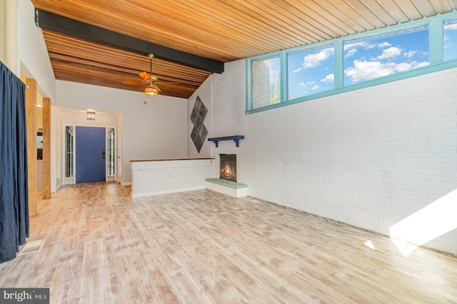 unfurnished living room with wooden ceiling, brick wall, a fireplace, wood finished floors, and beamed ceiling