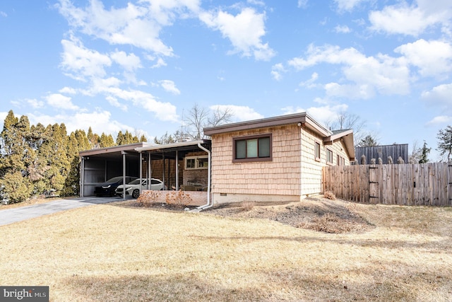 view of front facade with an attached carport, fence, and aphalt driveway