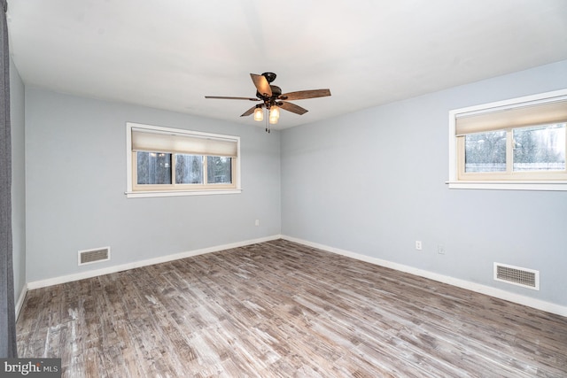 spare room featuring baseboards, visible vents, and wood finished floors