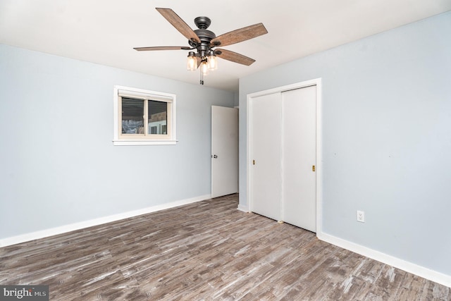 unfurnished bedroom featuring ceiling fan, a closet, wood finished floors, and baseboards