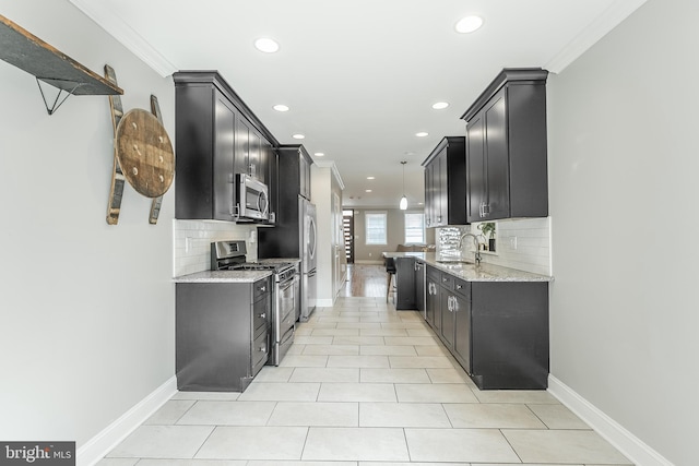 kitchen with a sink, dark cabinets, appliances with stainless steel finishes, and crown molding