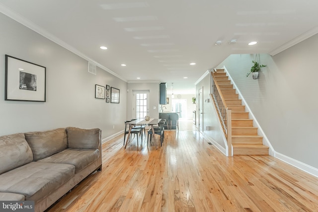 living area featuring light wood finished floors, baseboards, ornamental molding, stairs, and recessed lighting