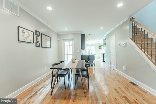 dining room with light wood-style flooring, visible vents, and baseboards