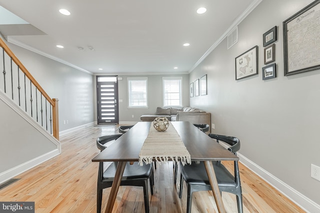 dining space with baseboards, visible vents, ornamental molding, wood finished floors, and stairs