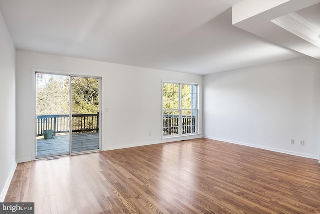 empty room featuring visible vents, baseboards, and wood finished floors