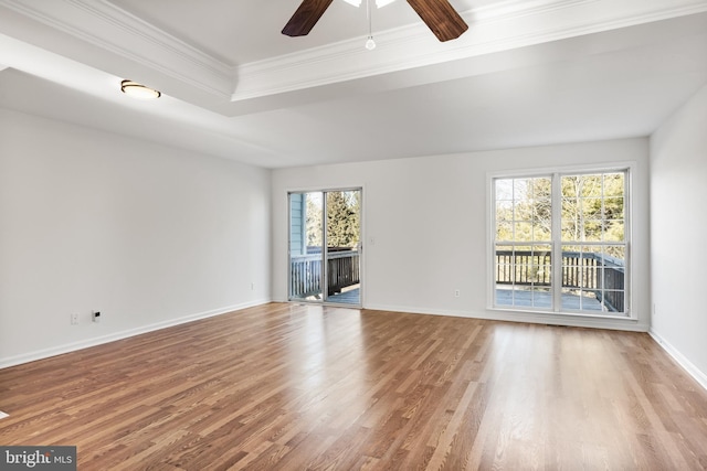 unfurnished living room with ceiling fan, wood finished floors, baseboards, ornamental molding, and a raised ceiling