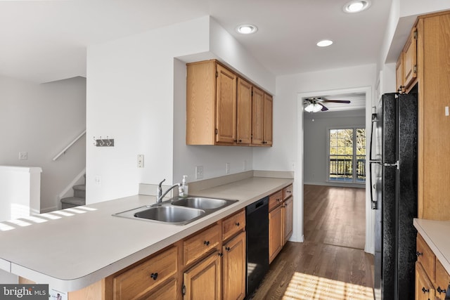 kitchen with black appliances, a peninsula, a sink, and light countertops