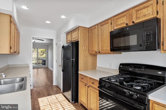 kitchen featuring a sink, black appliances, wood finished floors, and light countertops