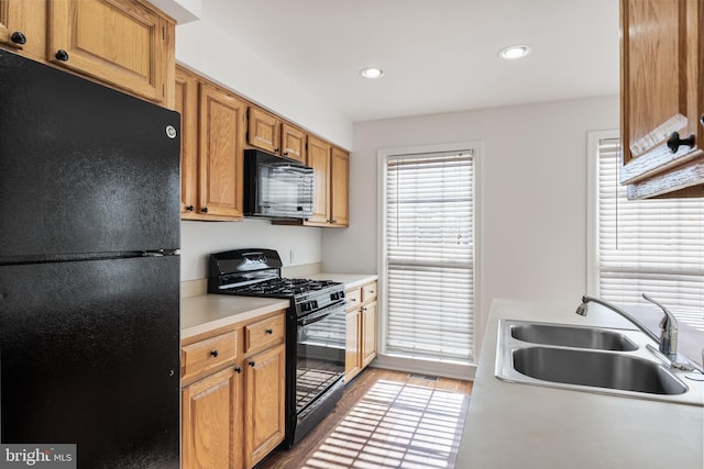 kitchen featuring black appliances, light countertops, a sink, and wood finished floors