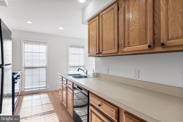 kitchen with brown cabinetry, light countertops, a sink, and black appliances