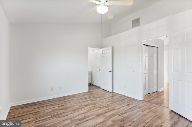 unfurnished bedroom featuring light wood finished floors, baseboards, visible vents, a ceiling fan, and vaulted ceiling