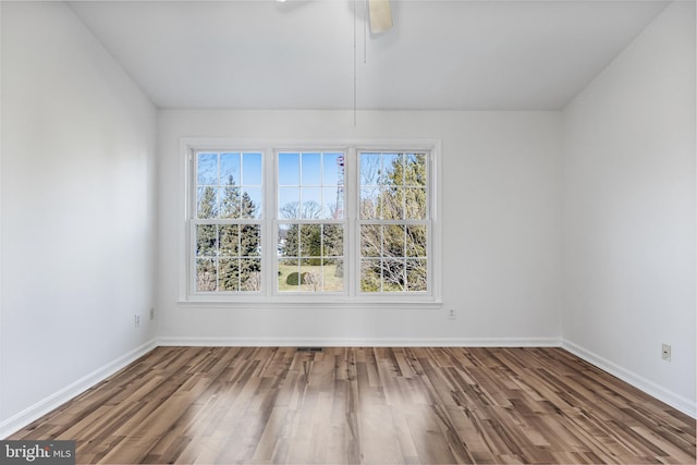 empty room with wood finished floors, visible vents, and baseboards