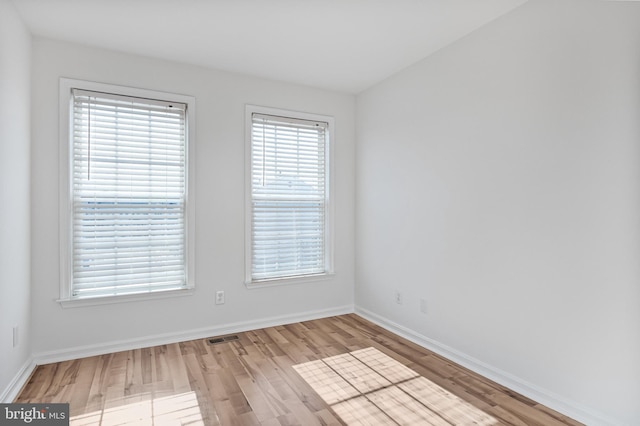 empty room featuring light wood-type flooring, baseboards, and visible vents