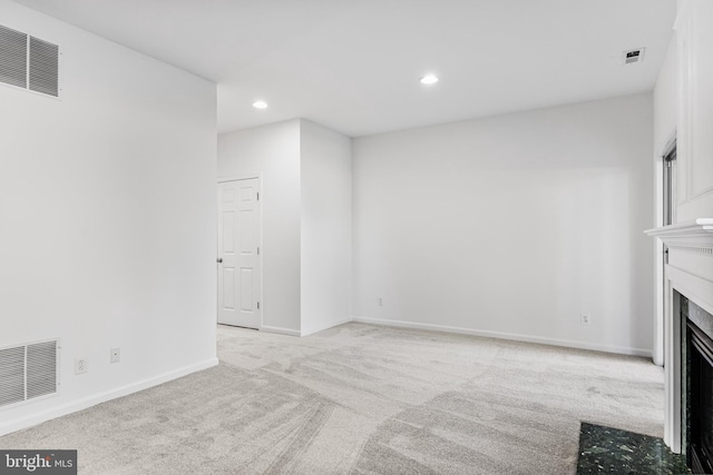 unfurnished living room with a fireplace with flush hearth, visible vents, and light carpet