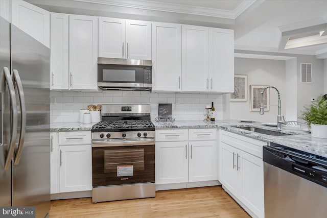 kitchen featuring stainless steel appliances, a sink, visible vents, white cabinets, and crown molding