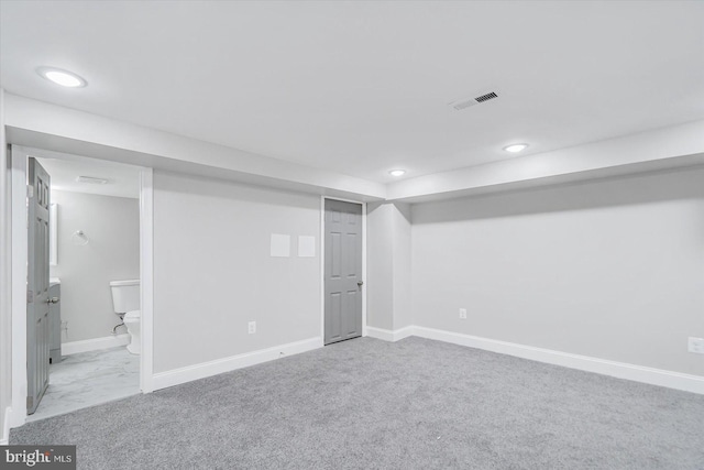 finished basement with light carpet, visible vents, baseboards, and recessed lighting