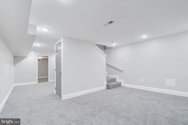 finished basement with light colored carpet, stairway, and baseboards