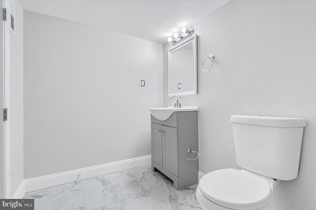 half bath with marble finish floor, toilet, vanity, and baseboards