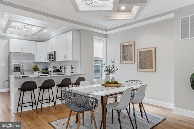 dining room featuring baseboards, visible vents, coffered ceiling, crown molding, and light wood-style floors