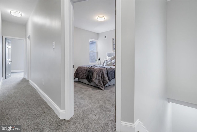 hall featuring light carpet, visible vents, and baseboards