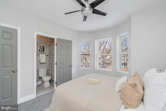 bedroom with ensuite bathroom, ceiling fan, carpet flooring, and baseboards