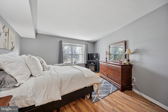 bedroom featuring multiple windows, baseboards, and wood finished floors