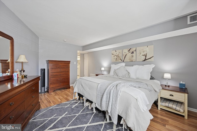 bedroom featuring light wood finished floors, visible vents, and baseboards