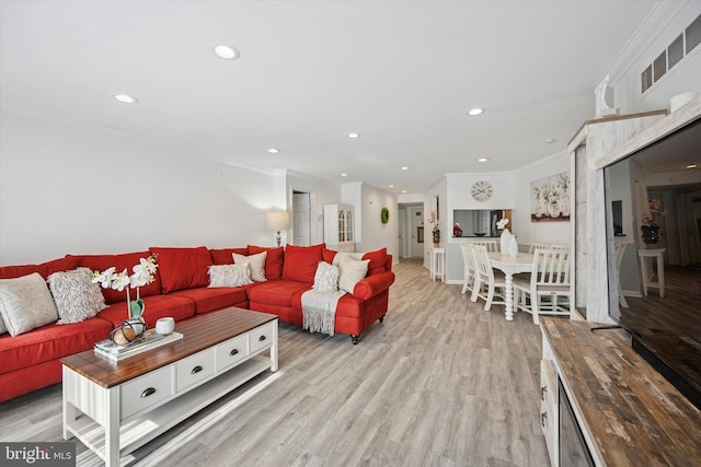 living room featuring light wood-style floors, visible vents, crown molding, and recessed lighting