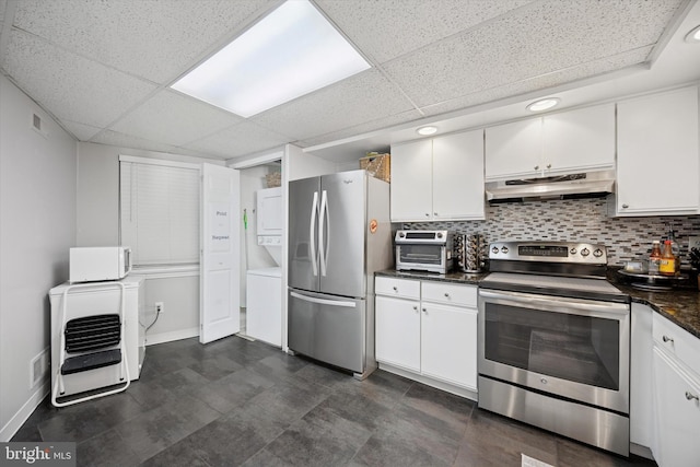 kitchen with tasteful backsplash, dark countertops, appliances with stainless steel finishes, white cabinetry, and under cabinet range hood