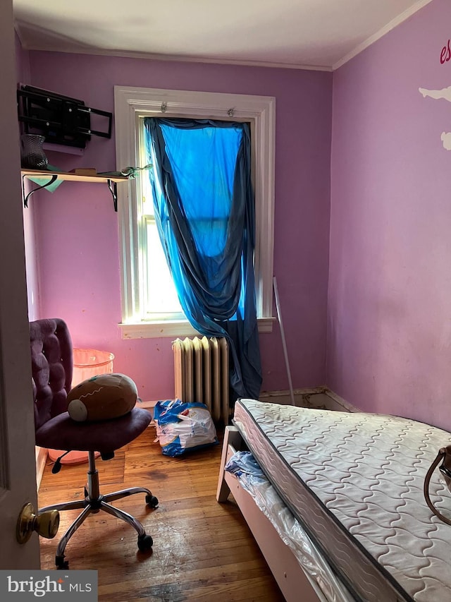 bedroom with radiator, crown molding, and wood finished floors