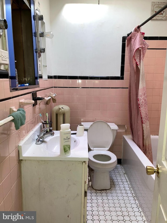 bathroom featuring toilet, vanity, tile walls, tile patterned floors, and shower / bath combo