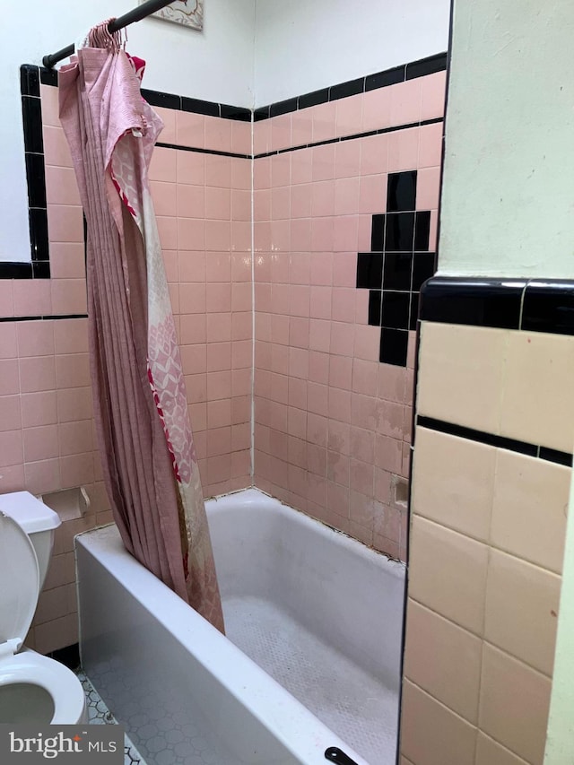 full bathroom with shower / bath combo with shower curtain, toilet, and tile walls