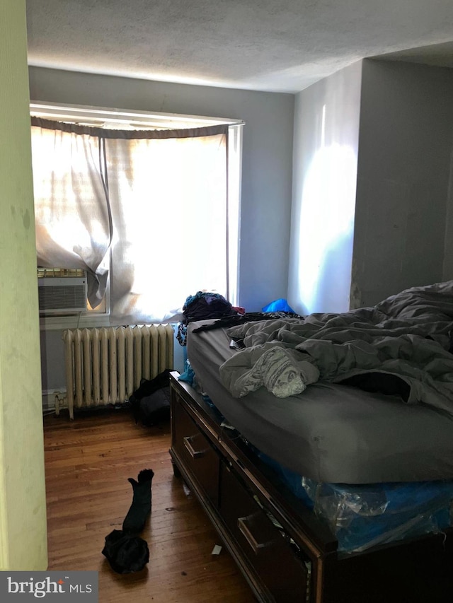 bedroom featuring radiator, a textured ceiling, and wood finished floors