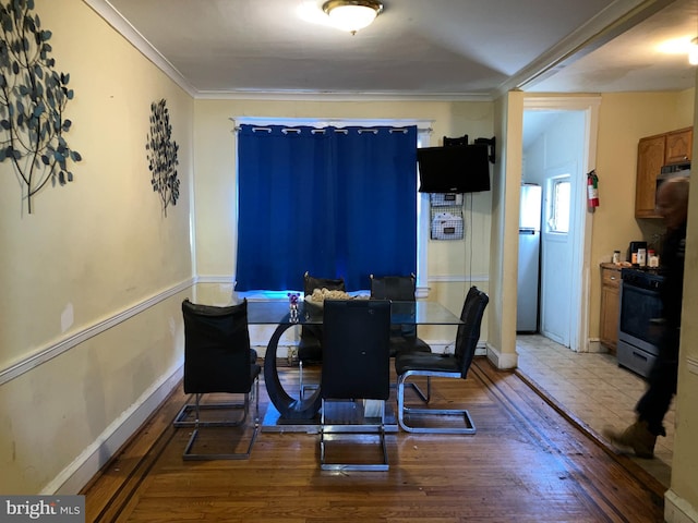 dining room with ornamental molding, baseboards, and wood finished floors