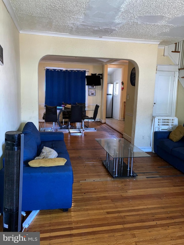 living area with ornamental molding, arched walkways, a textured ceiling, and hardwood / wood-style flooring