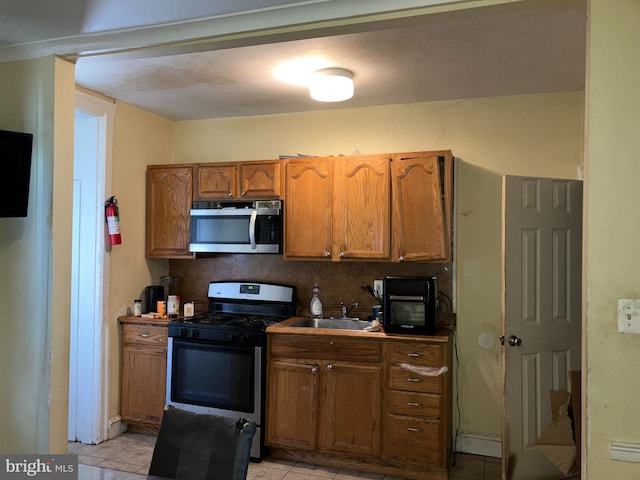 kitchen featuring brown cabinetry, stainless steel appliances, and a sink