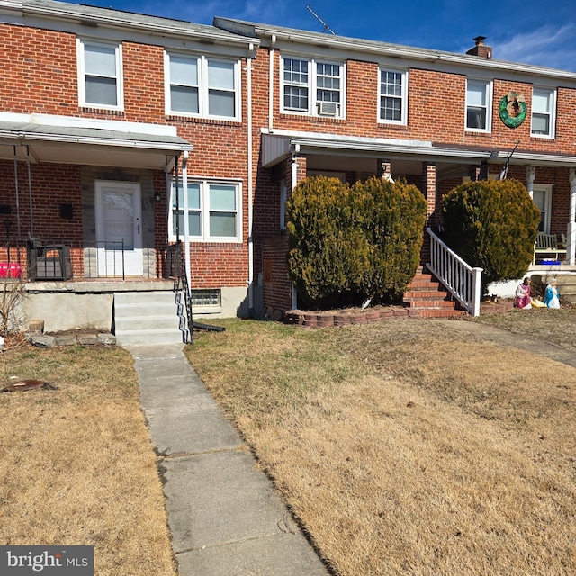 view of property featuring brick siding, a porch, and a front yard