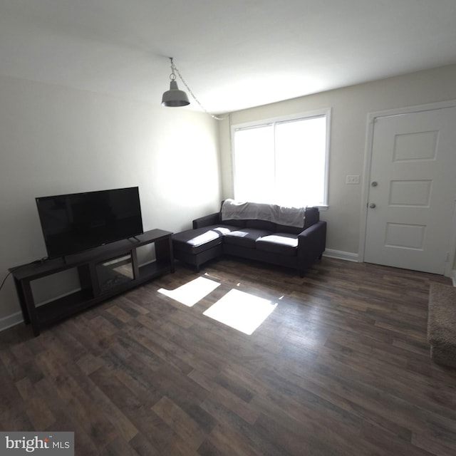 unfurnished living room featuring wood finished floors and baseboards