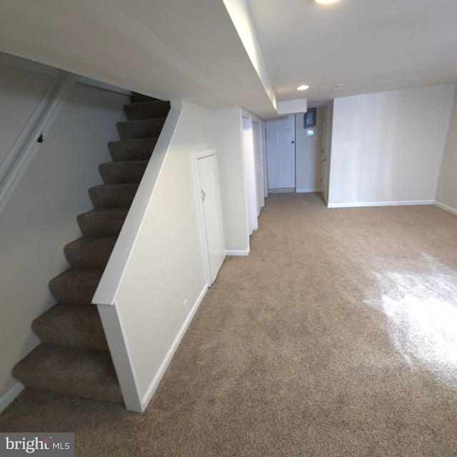 finished below grade area featuring recessed lighting, light carpet, stairway, and baseboards