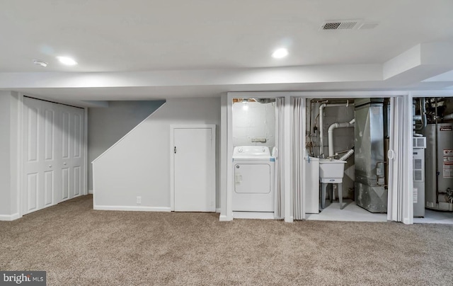 finished basement with carpet floors, washer and clothes dryer, gas water heater, and visible vents