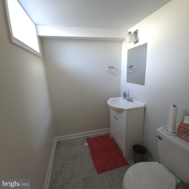 half bath with toilet, tile patterned flooring, baseboards, and vanity