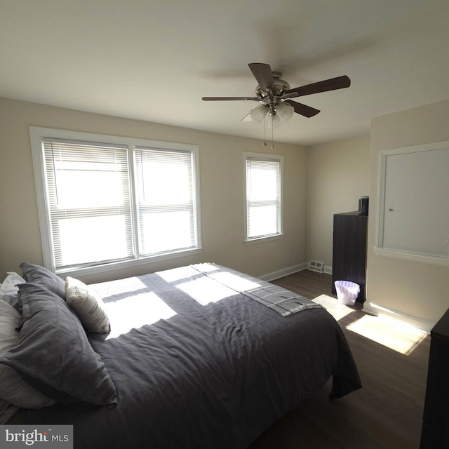 bedroom featuring baseboards, ceiling fan, visible vents, and dark wood-type flooring