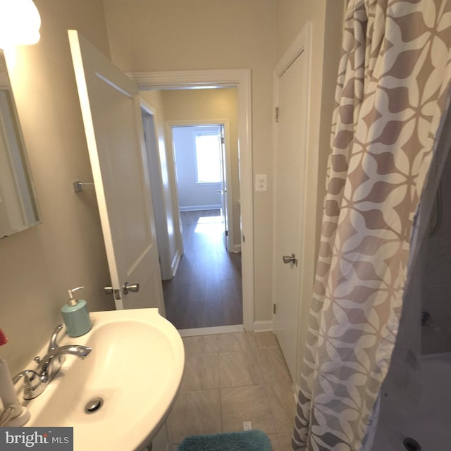 bathroom featuring tile patterned floors, baseboards, a sink, and a shower with shower curtain