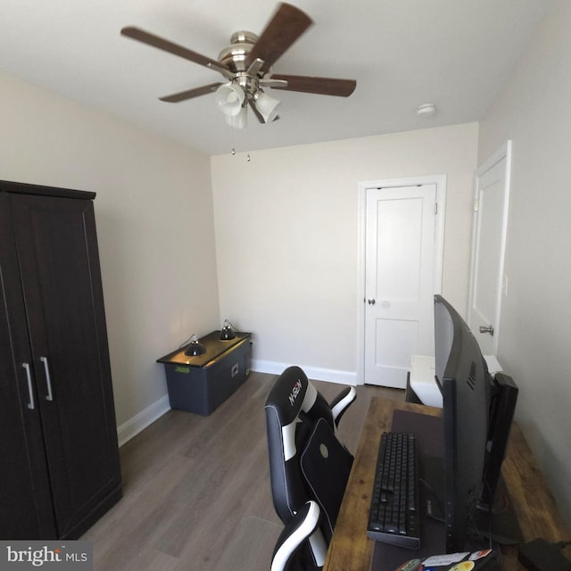 interior space featuring ceiling fan, baseboards, and wood finished floors