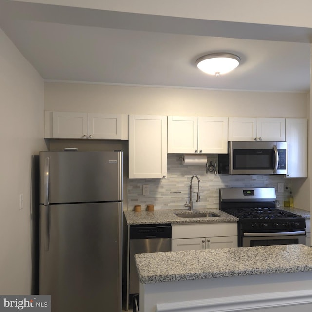 kitchen featuring decorative backsplash, white cabinetry, stainless steel appliances, and a sink