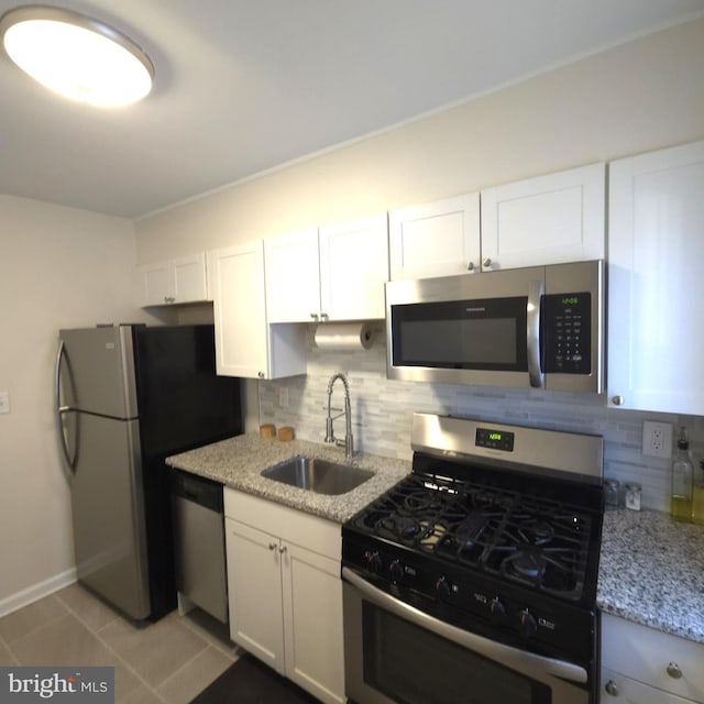 kitchen featuring appliances with stainless steel finishes, white cabinetry, a sink, and decorative backsplash