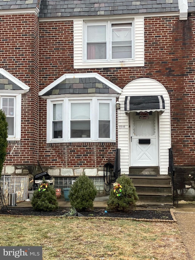 townhome / multi-family property with brick siding and roof with shingles